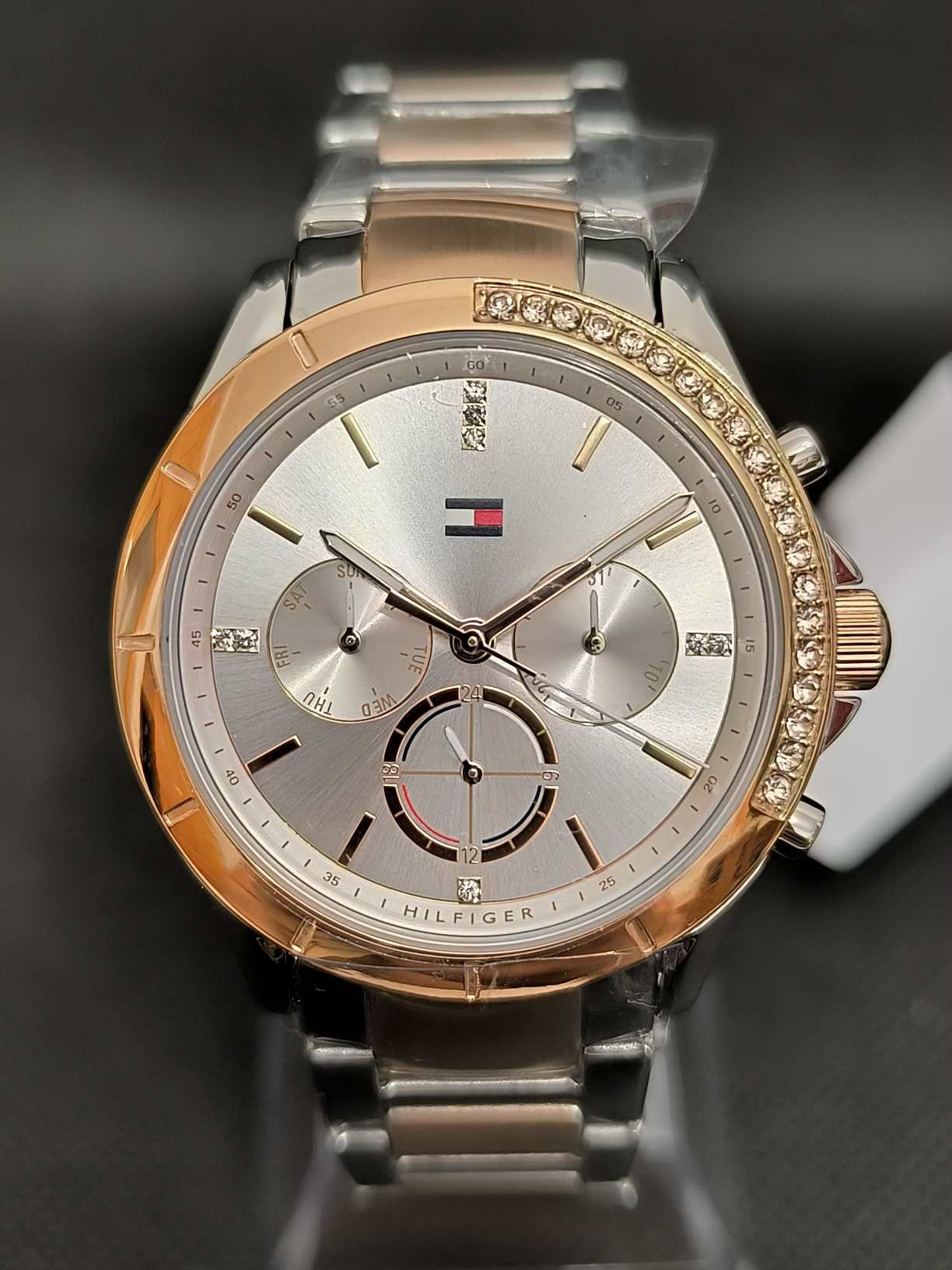 Reloj Tommy Hilfiger Kennedy TH1782387 con caja de 38 mm rosada con cristales brillantes, esfera plateada, y correa de eslabones bicolor en plateado y rosado.