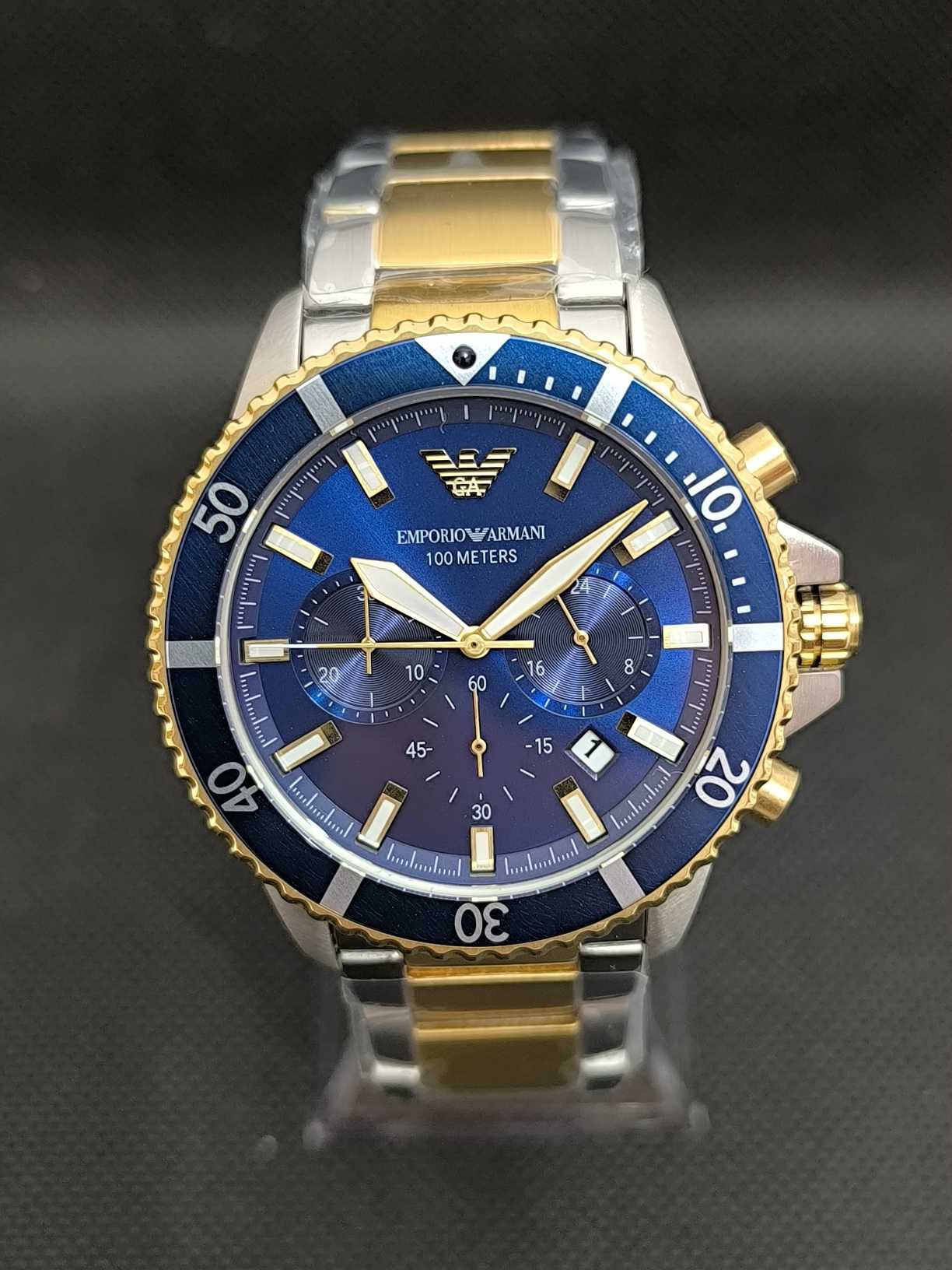 Reloj Emporio Armani Diver AR11362 cronógrafo con caja de acero inoxidable de 43 mm, bisel giratorio azul y dorado, esfera azul con subesferas de cronógrafo y brazalete dorado, cuenta con un movimiento de cuarzo y una resistencia al agua de 100 metros (10 ATM), es ideal tanto para actividades acuáticas como para su uso diario.