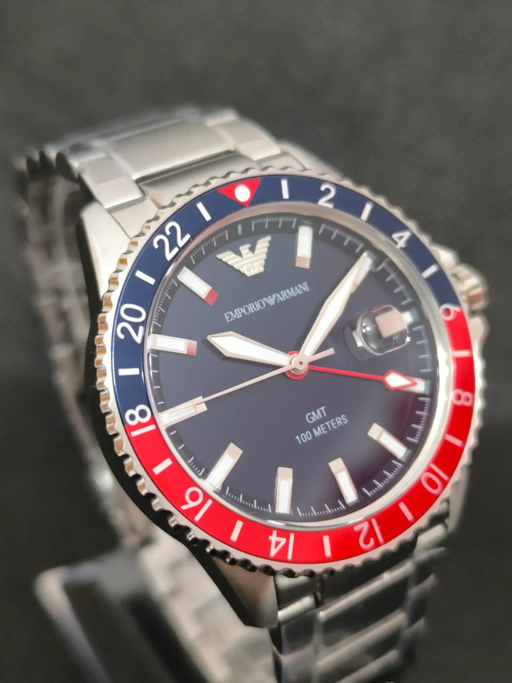 Reloj Emporio Armani Diver AR11590 GMT con bisel bicolor rojo y azul, función GMT y esfera azul con marcadores luminosos.